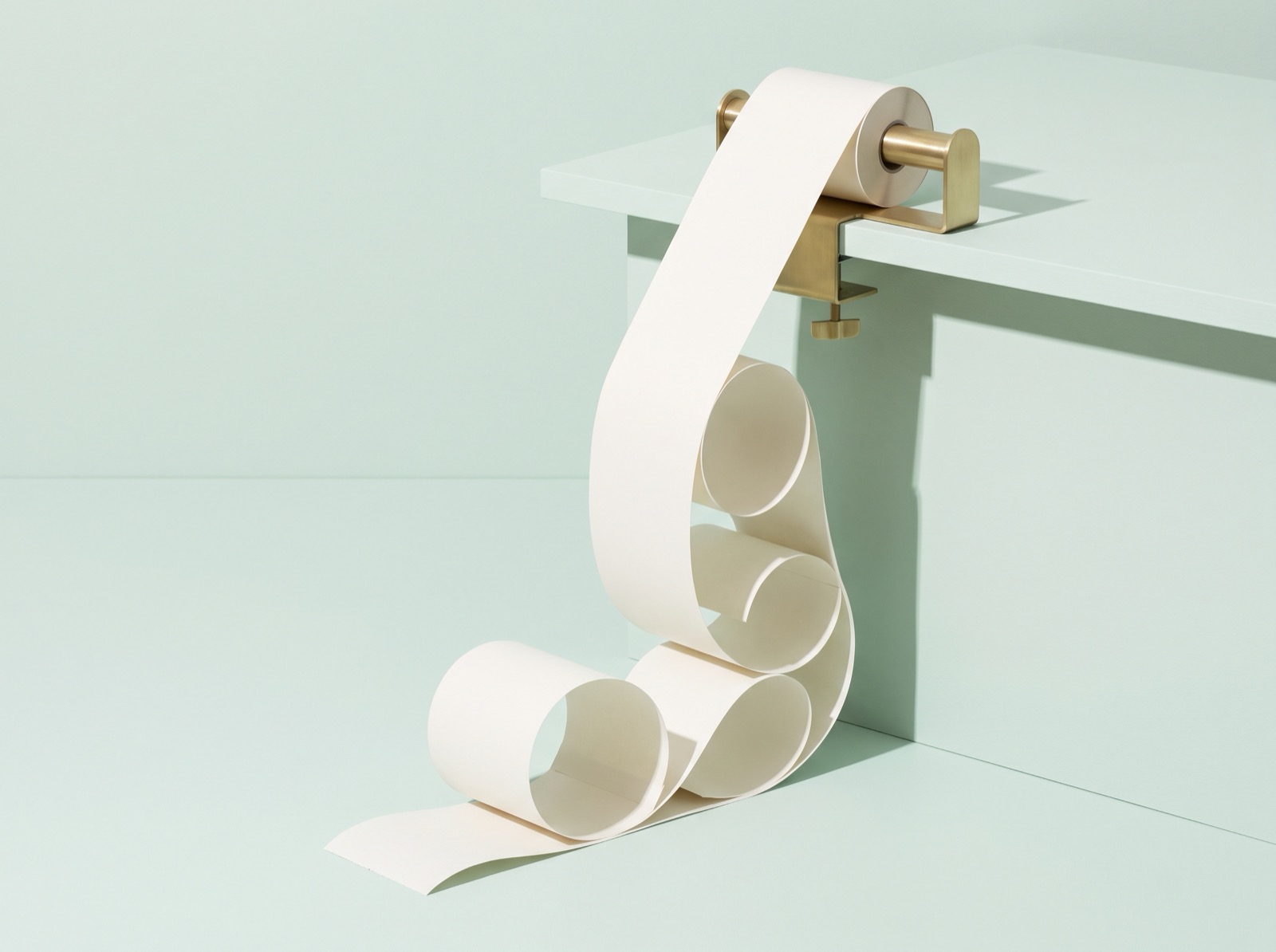 A long strip of blank adding-machine paper tape spilling off the edge of a mint-green desk and curling across the floor